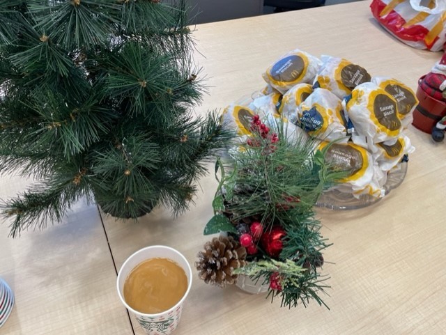 A cup of coffee and a plate of biscuits sitting on the table with Christmas decor